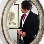 Reflection in mirror of Best man getting ready at Bovey Castle wedding in Devon.