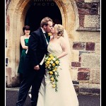 Bride and groom kiss outside church doorway at Plymouth wedding