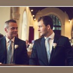 groom and bestman looking at each other nervously before wedding ceremony in Devon church