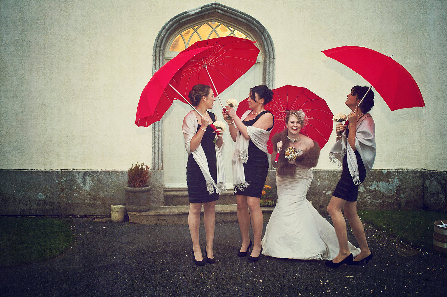 Bridesmaids with red umbrellas outside Haldon Belvedere in Devon