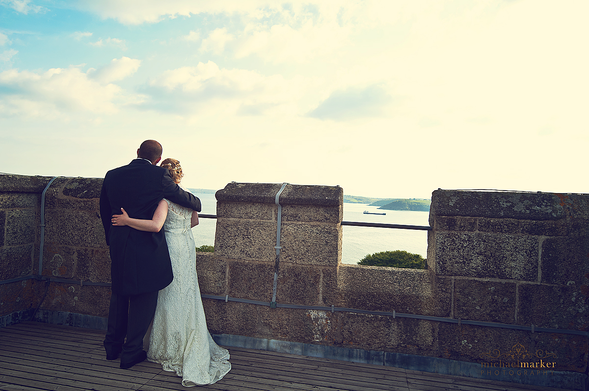 Couple at Falmouth wedding looking out from rooftop of Pendennis Castle.