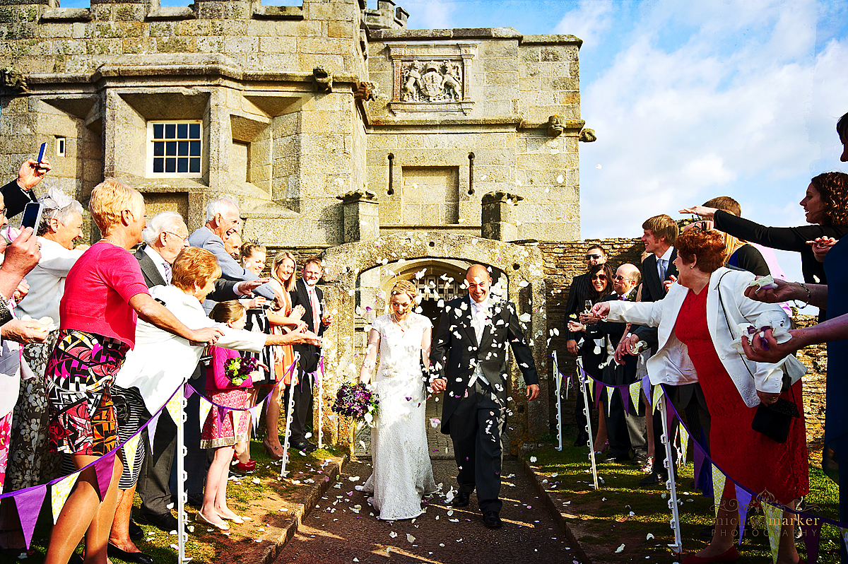 Confetti being thrown at couple as they leave Pendennis Castle entrance at Falmouth wedding