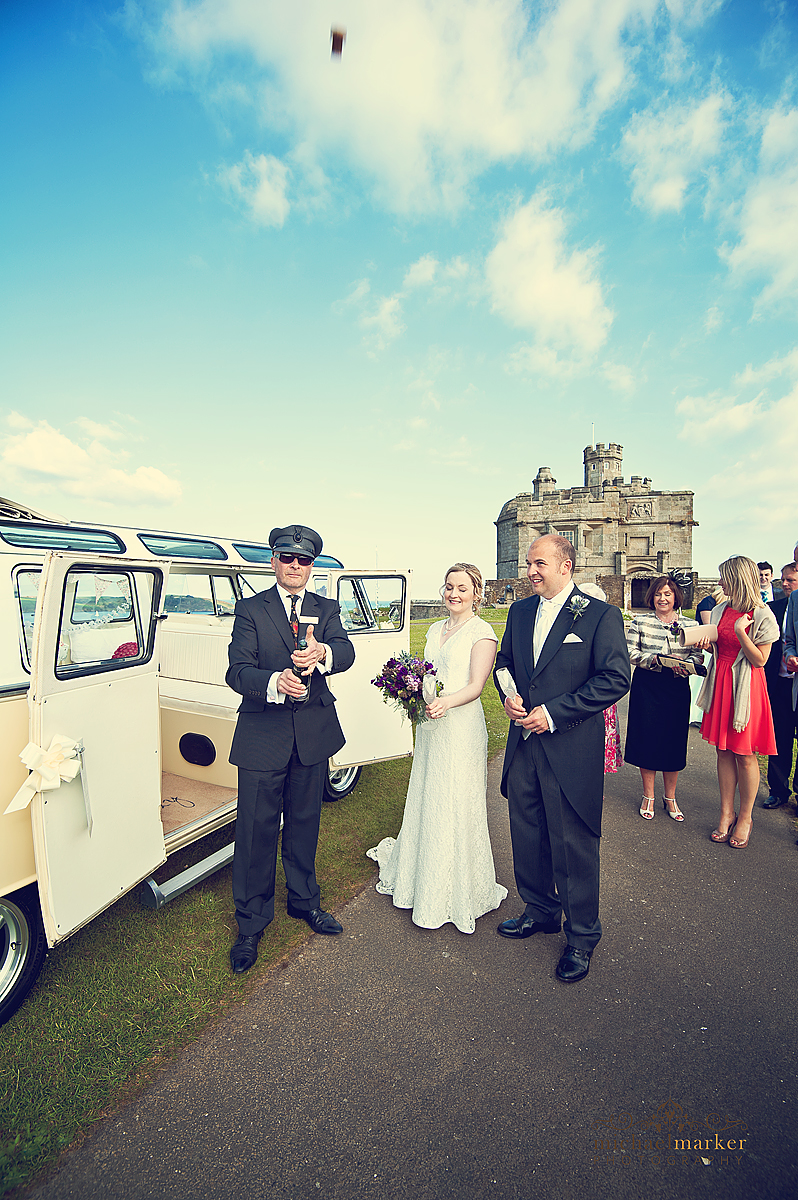 Bride and groom celebrating with champagne in front of Pendennis Castle in Cornwall