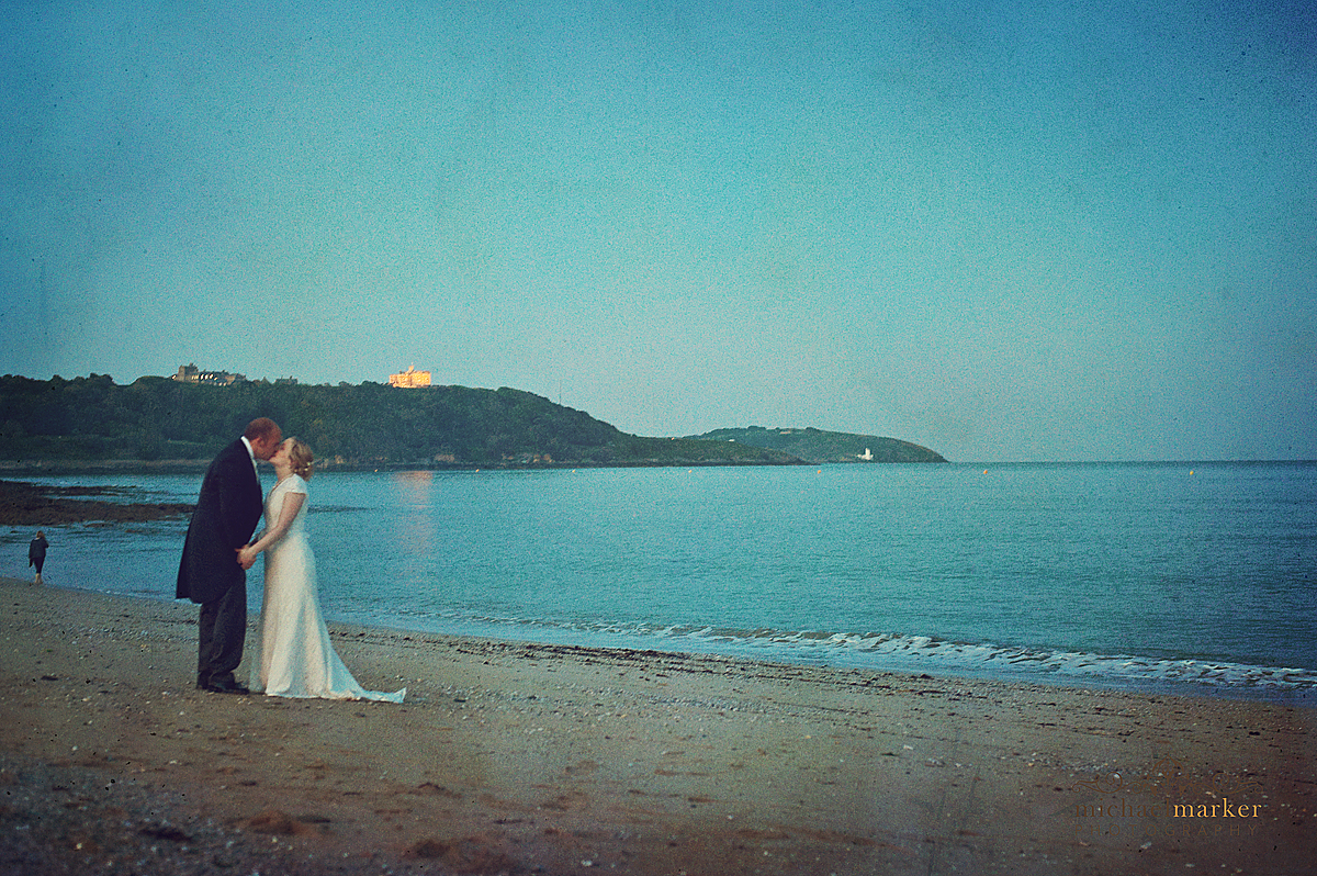 Bride and groom wedding photography on Falmouth beach on their wedding day with Pendennis Castle in the background.