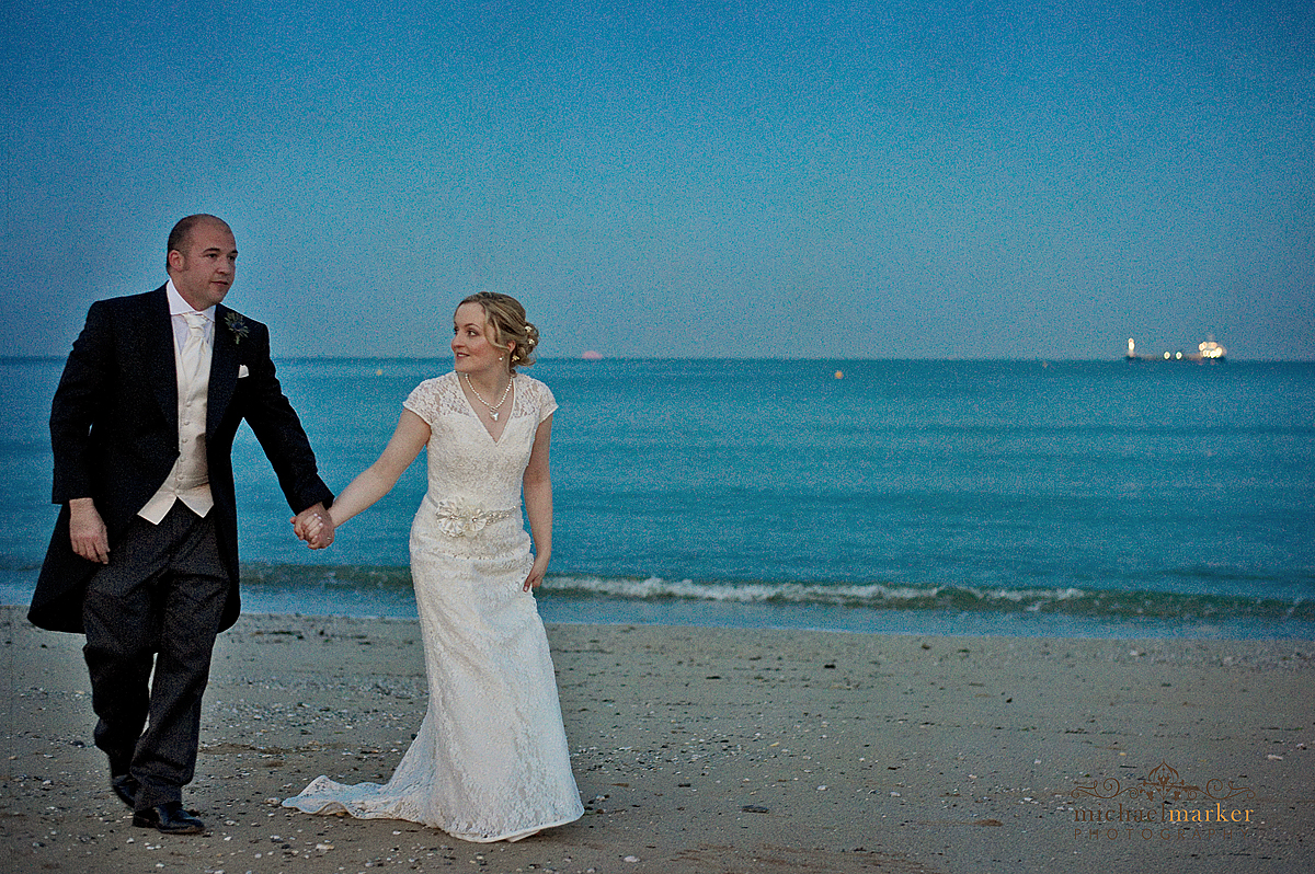 Cornish wedding couple walk on Falmouth beach at dusk.