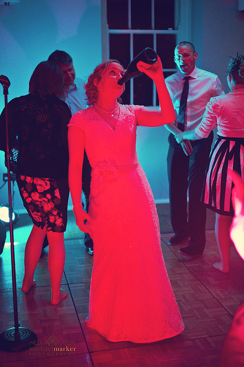 Falmouth wedding photo at Pendennis Castle wedding reception. Bride drinking from champagne bottle.