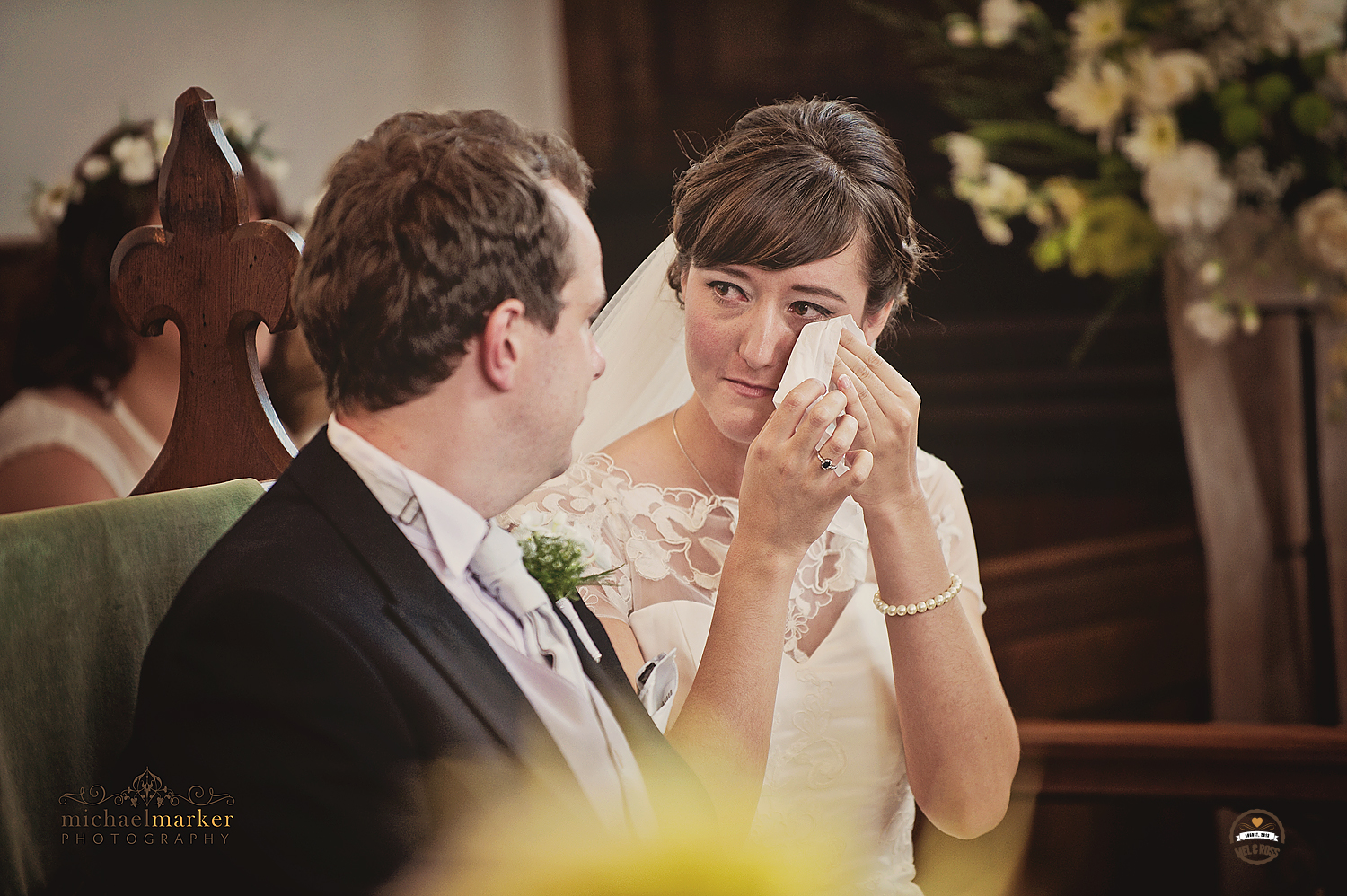 Bride wiping away tears during wedding ceremony