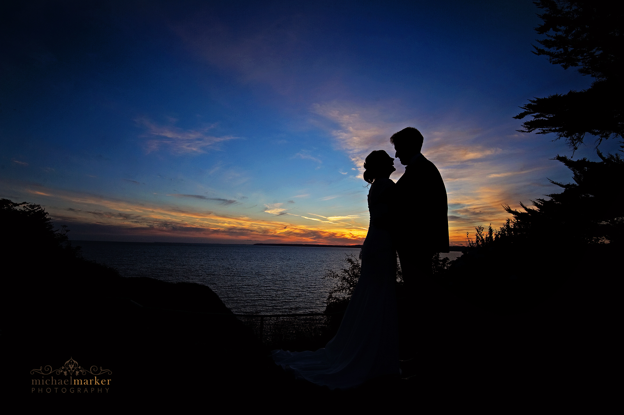 Bride and groom sunset silhouette embracing at Polhawn Fort