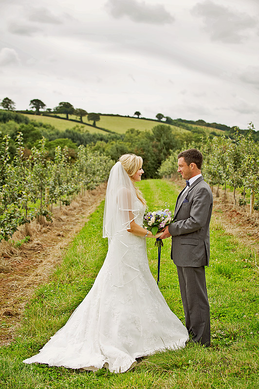 Bride and groom looking at each other in Orchards at Corn Barn in Devon
