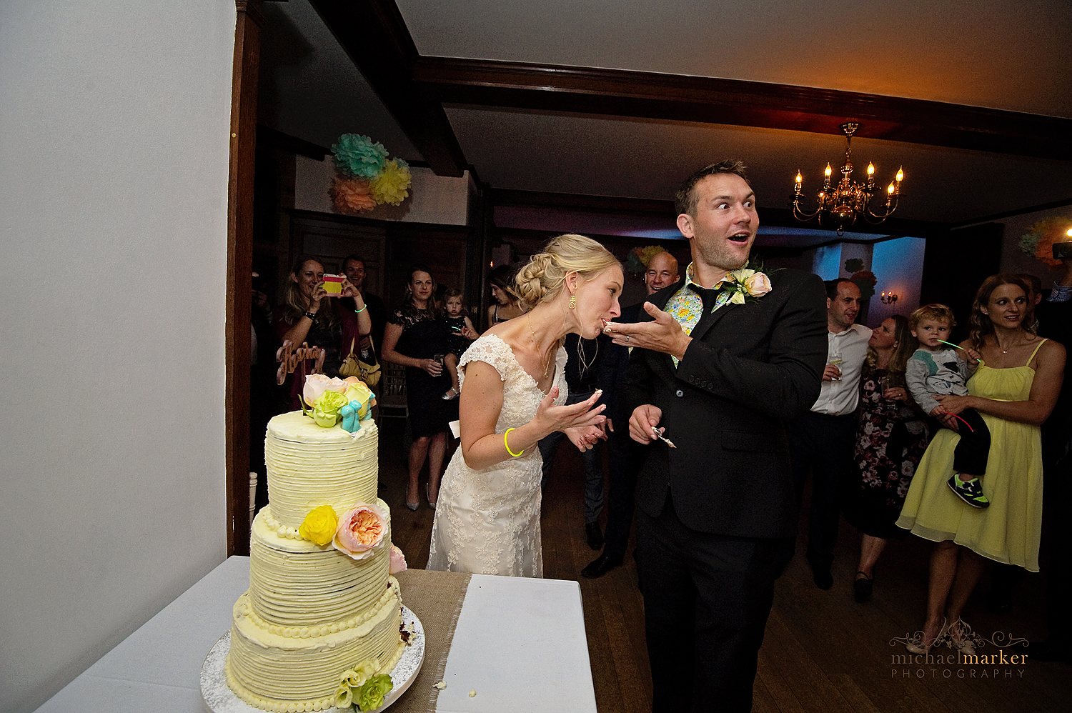 Bride licking cake off grooms fingers during cake cutting at wedding