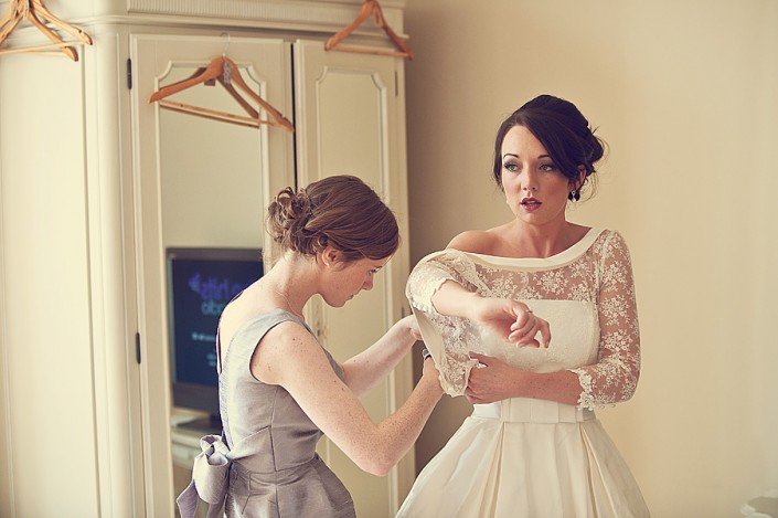 Bride putting her wedding dress on in the honeymoon suite at Langdon Court Hotel near Plymouth in Devon.