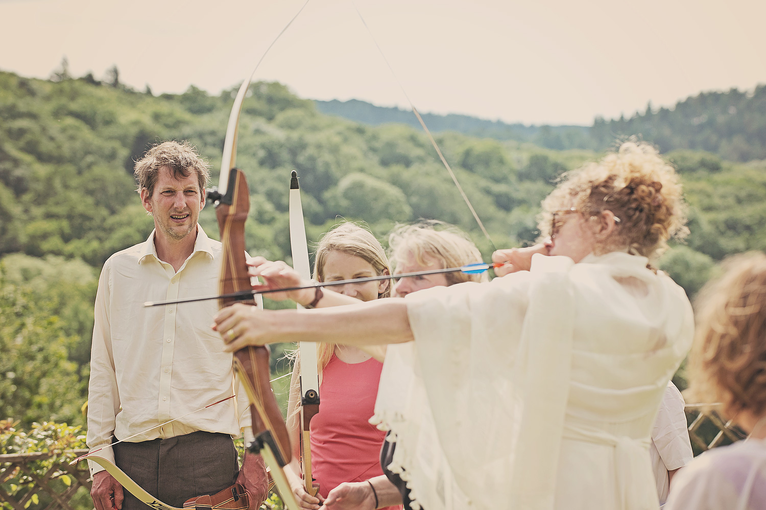 Bride taking part in archery at wedding celebrations at Hotel Endsleigh in Devon