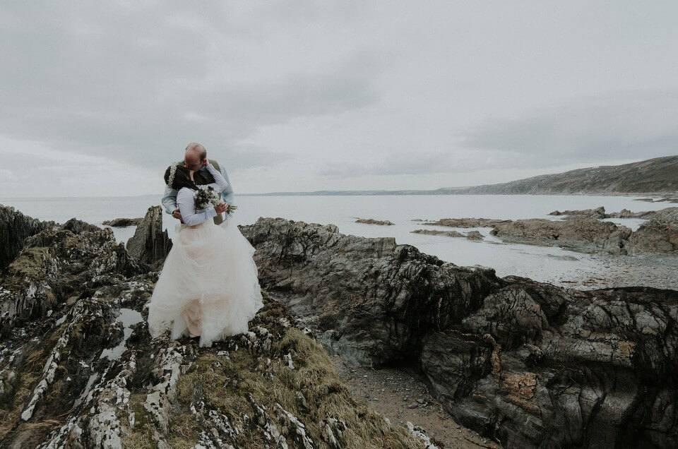 Bride and groom kiss on the beach at Polhawn Fort in Cornwall