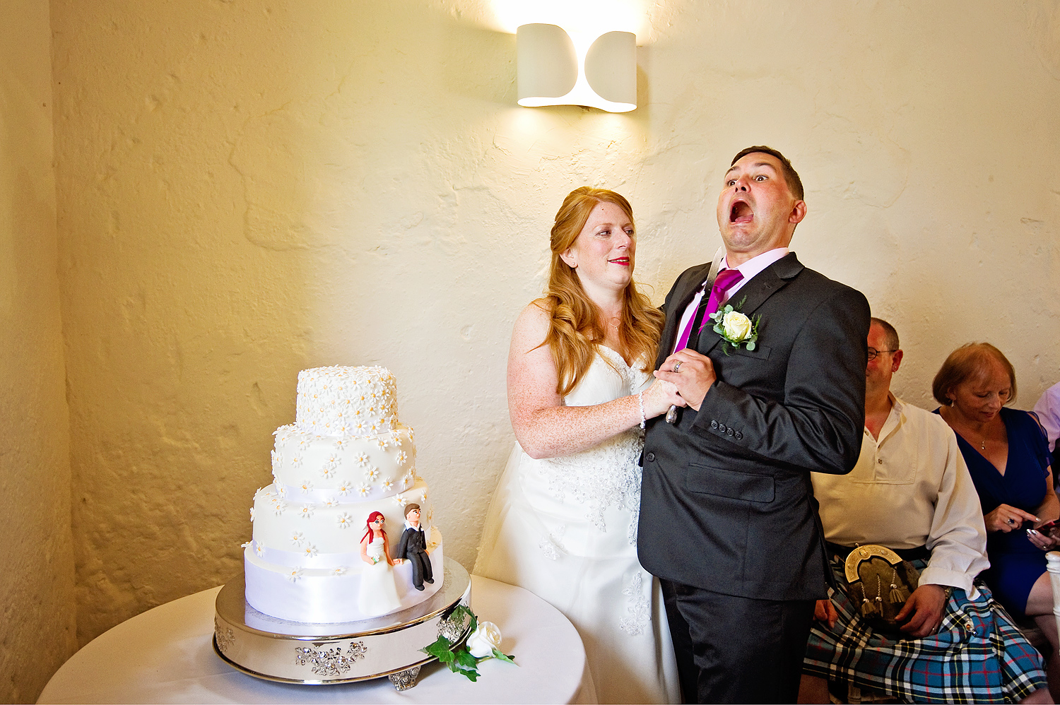 Funny cutting the cake photo at a Bath wedding as bride holds knife to groom's chin.