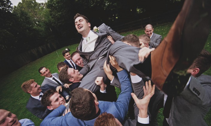 Groom being held aloft by his friends on his wedding day - documentary photo