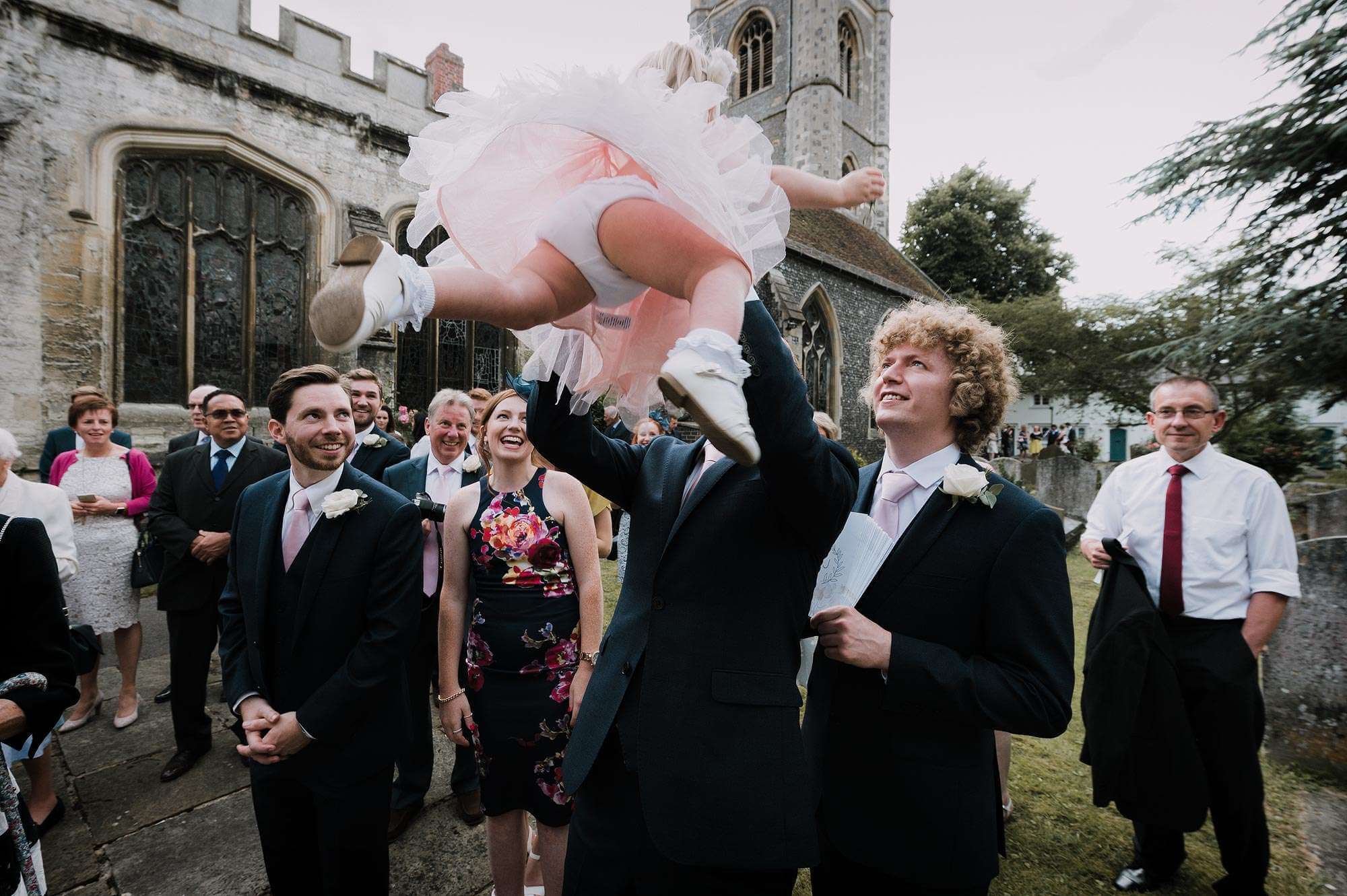 Henley on Thames documentary wedding moment as groom lifts up his daughter outside the church