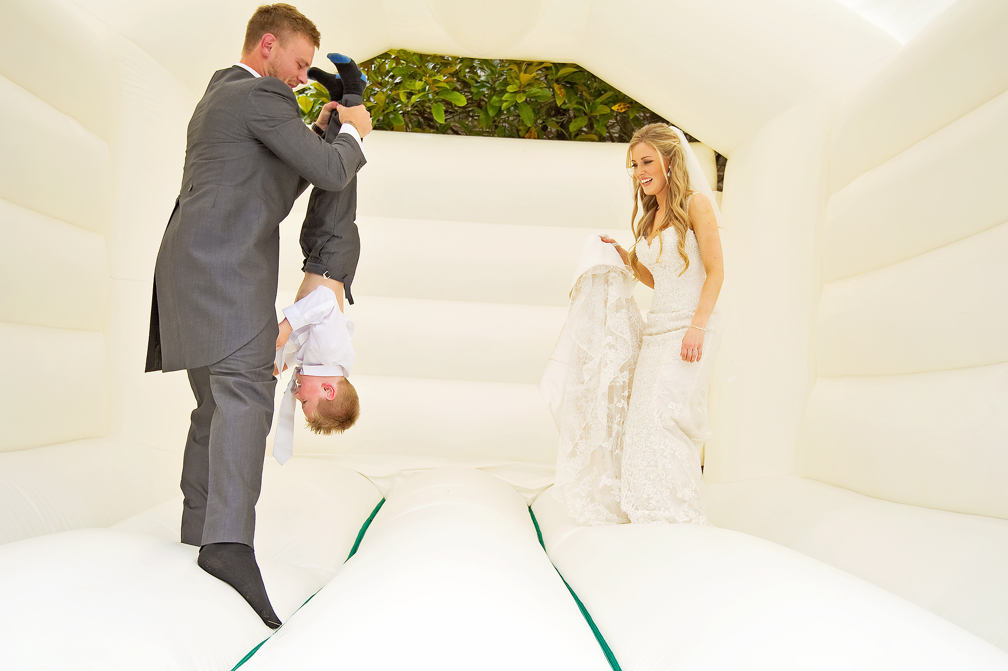 Bride and groom and usher on bouncy castle