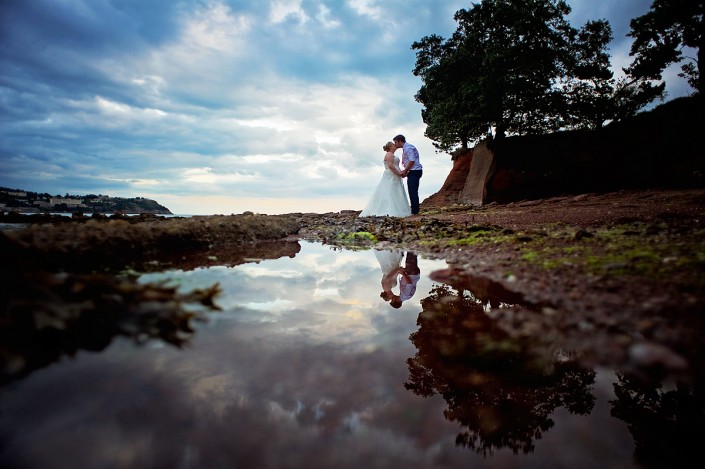 Bride and groom reflected in a rock pool at Torquay beach wedding.