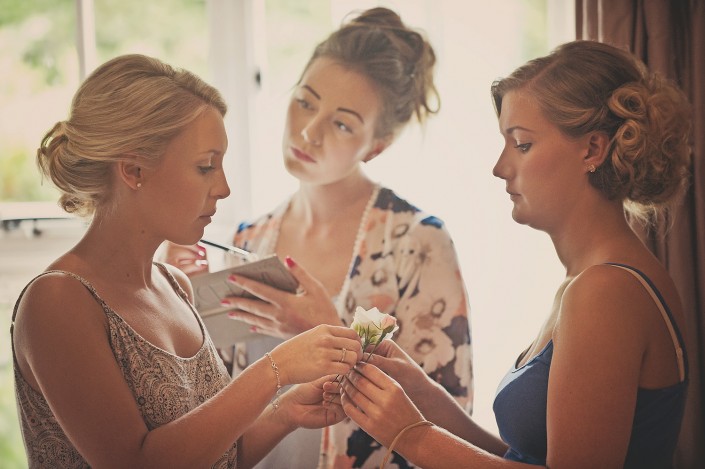 Bride and bridesmaids apply make up whilst getting ready for Tavistock wedding in Devon.