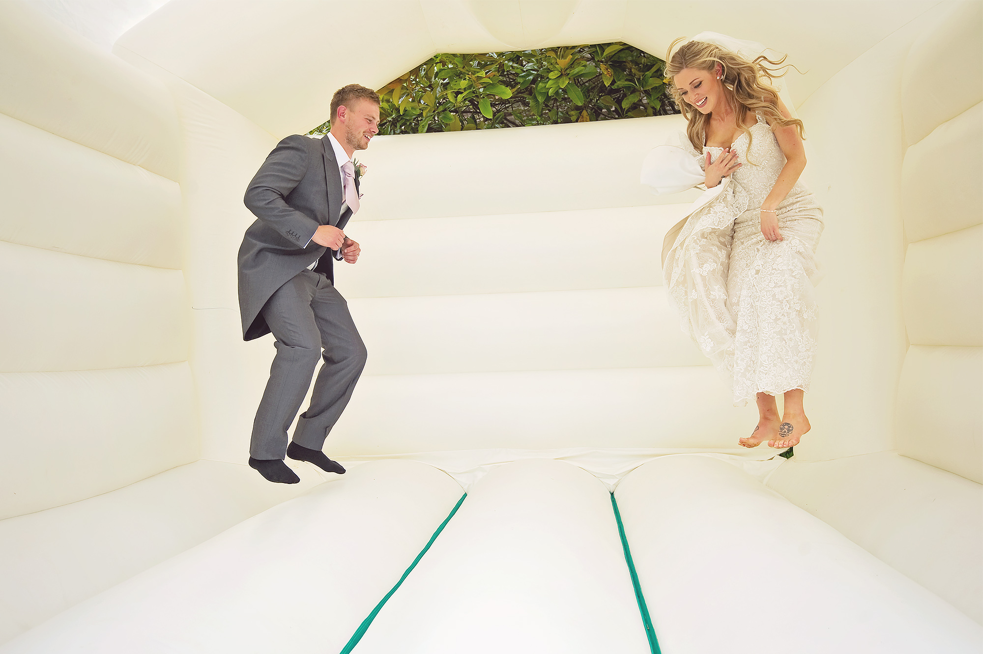 Bride and groom jumping on bouncy castle at Devon country house wedding