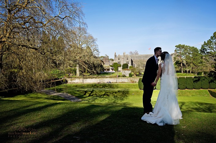 Bride and groom kiss in gardens at Dartington Hall