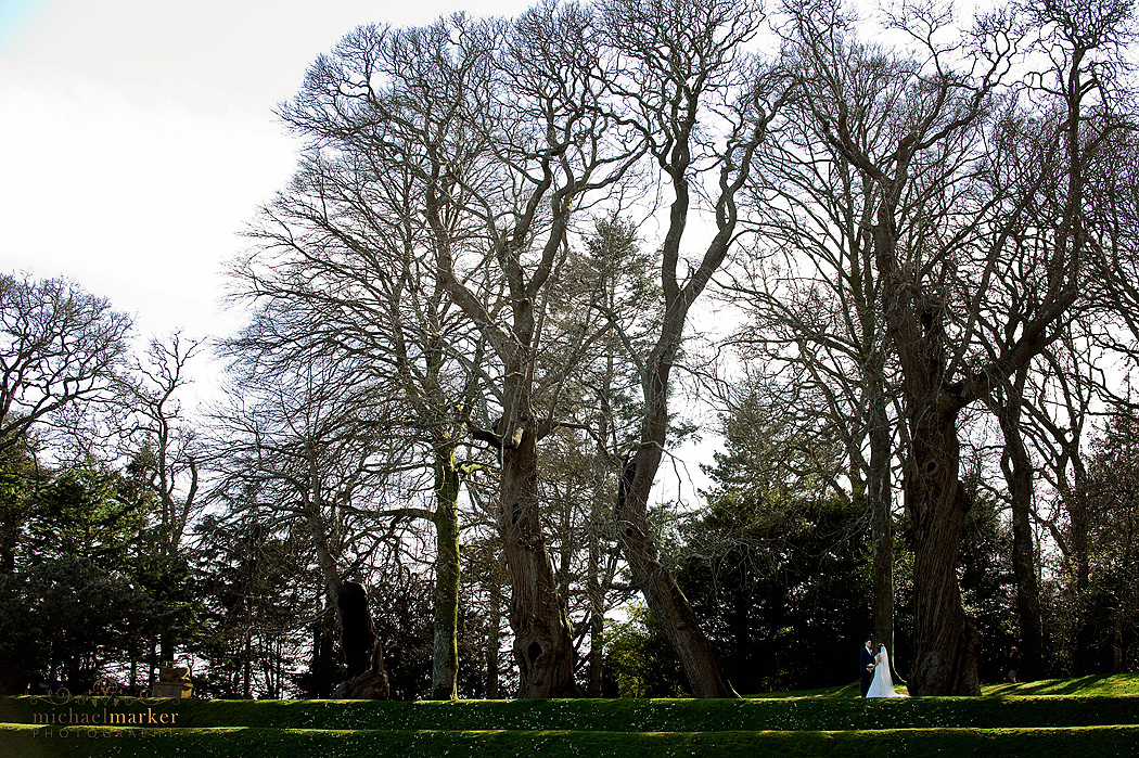 Bride and groom on garden terraces at Dartington Hall in Devon