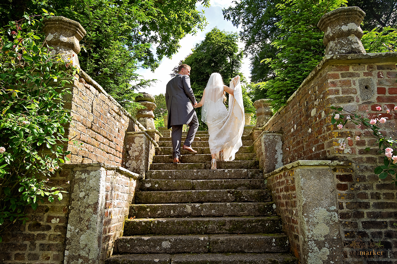 Bride and groom walk up the garden steps at Langdon Court