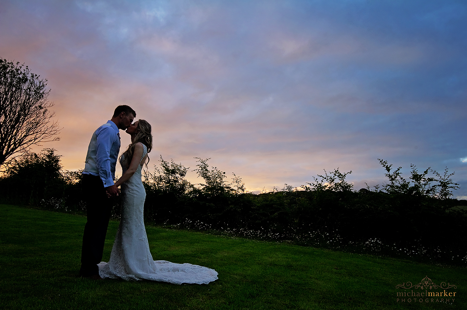 Bride and groom kiss at sunset at Langdon Court wedding