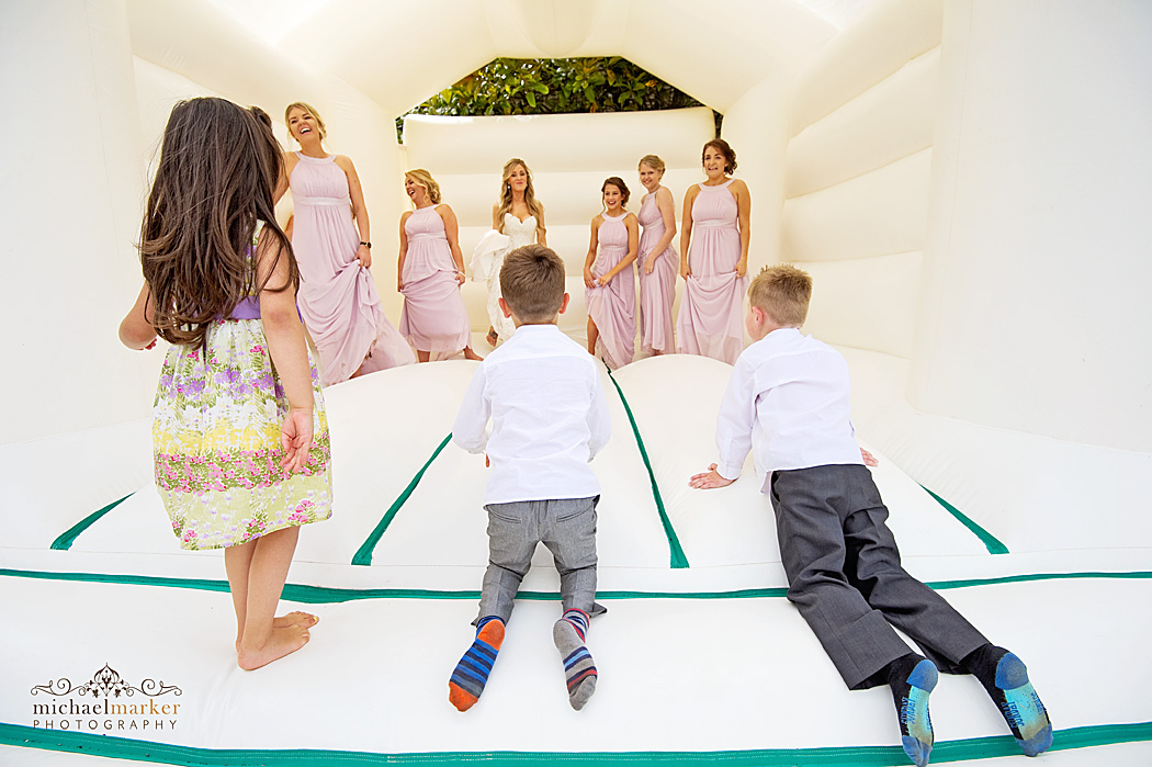 Kids watching bride and bridesmaids on bouncy castle at Devon wedding