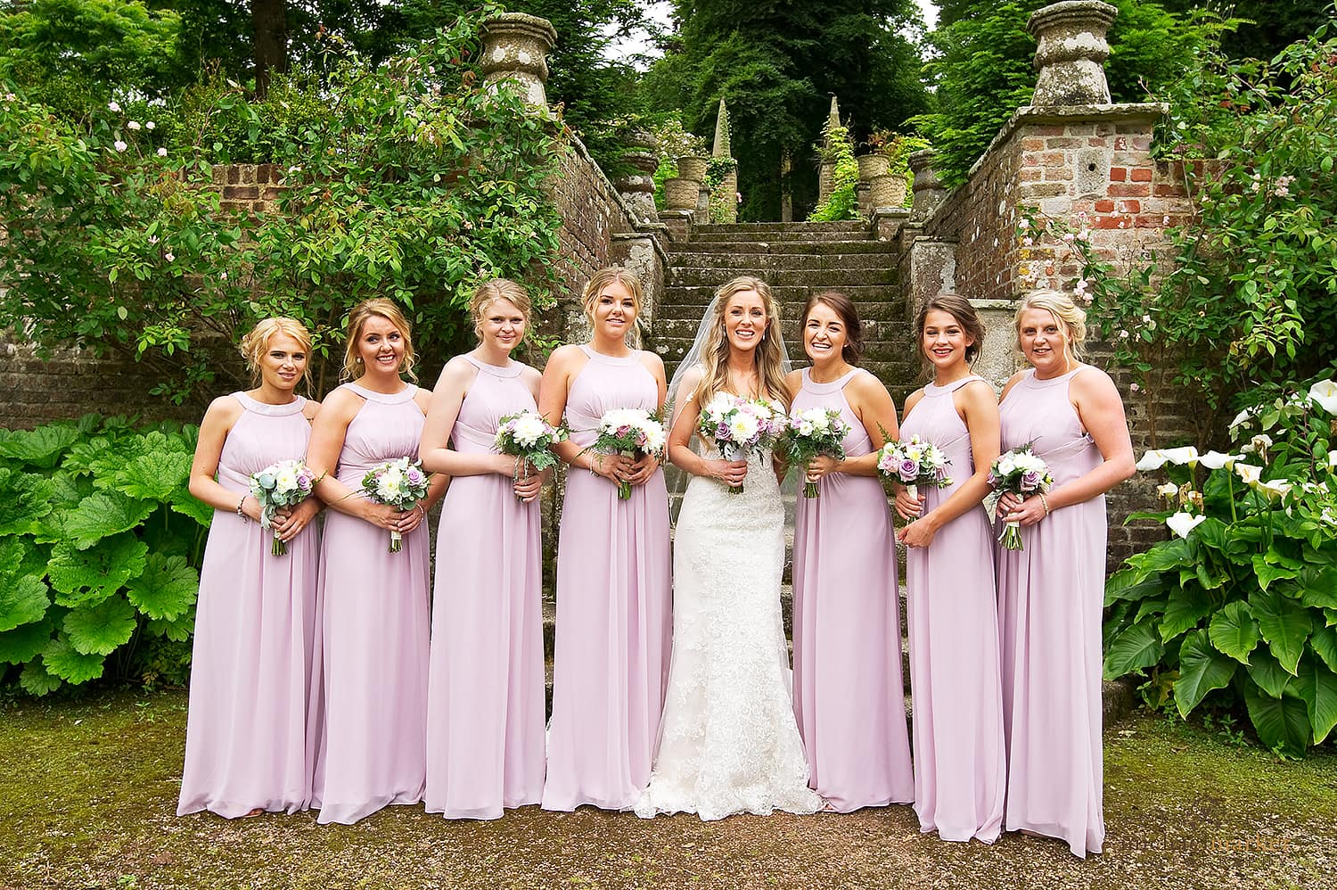 Bride and bridesmaids in pink dresses in gardens of Langdon Court in Devon.