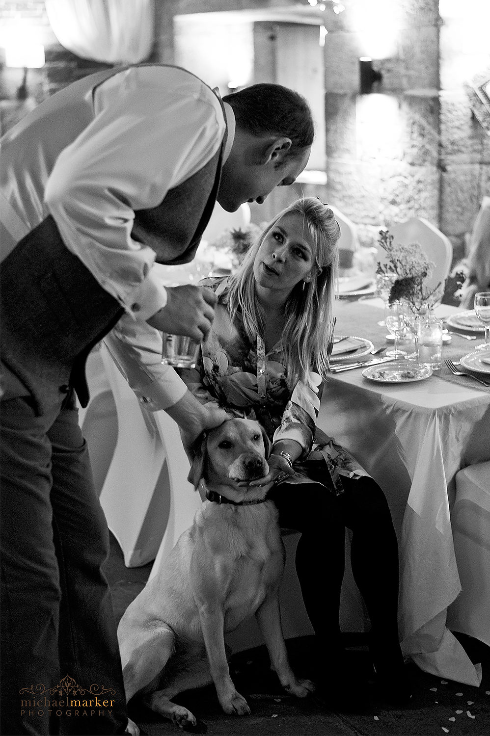 groom talking to wedding guest and patting dog