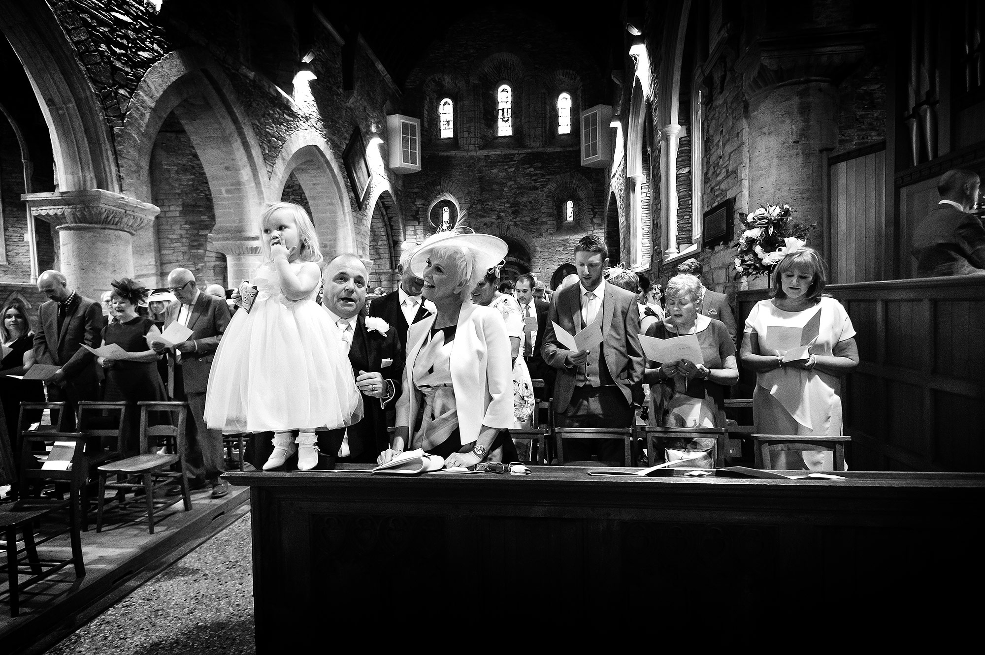 Flowergirl eating sweets during wedding ceremony at St Germans curch in Cornwall