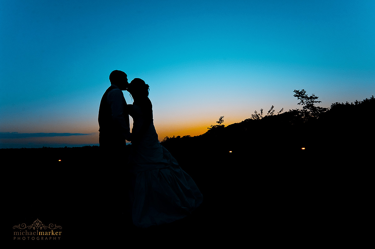 Sunset silhouette of bride and groom kissing