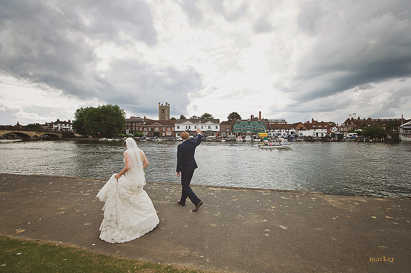 Bride and groom wave to paeer bys on the river at Henley-on-Thames wedding