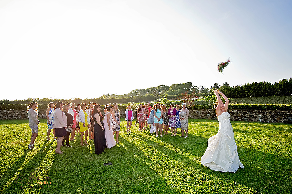 Bride throwing her wedding bouquet at Lifton farm shop