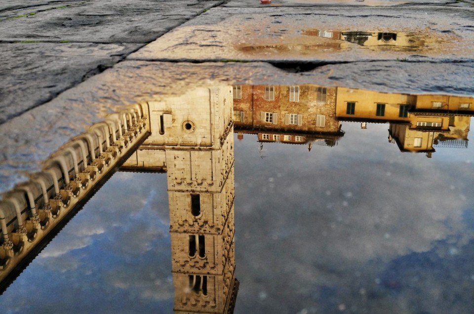 Mobile phone photo of church tower in Lucca reflected in a puddle.