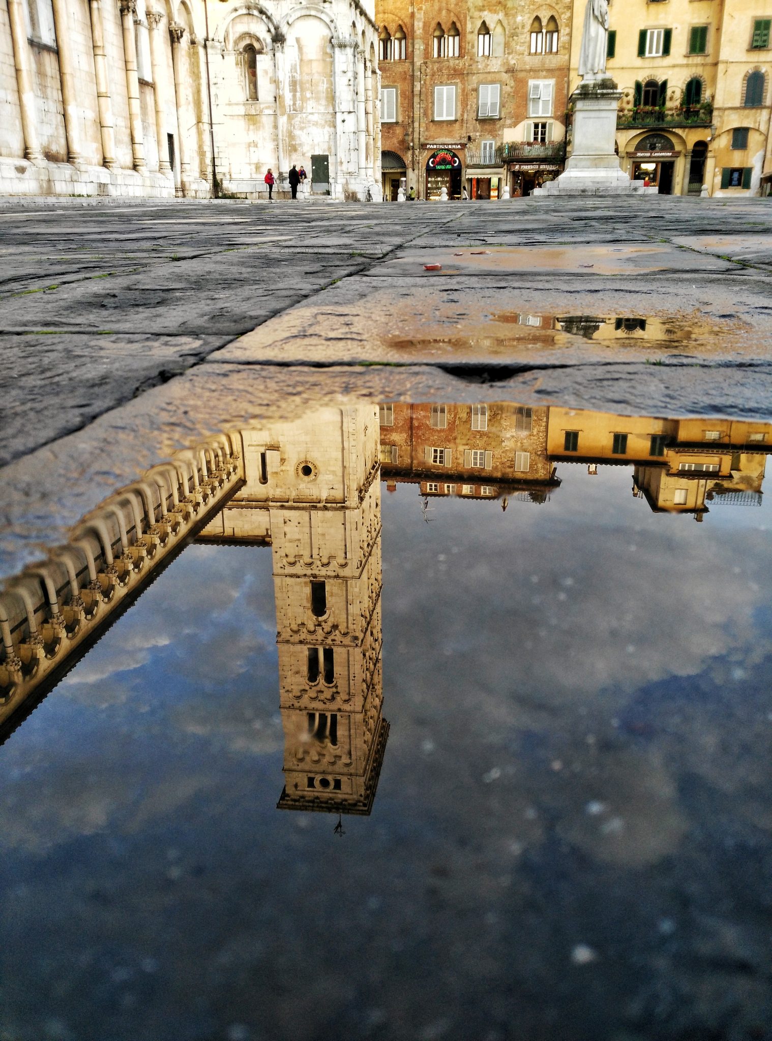 Mobile phone photo of church tower in Lucca reflected in a puddle.