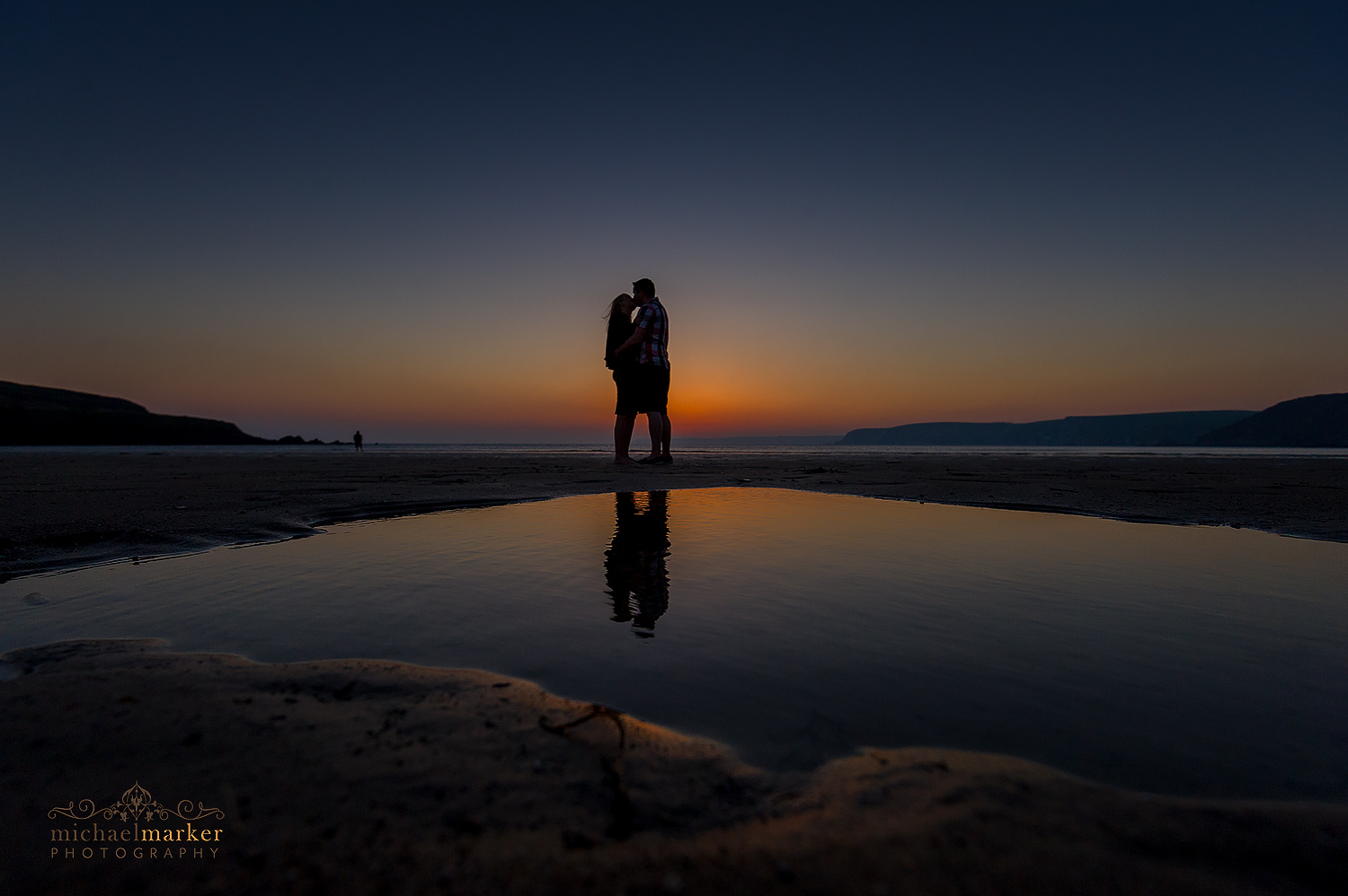 Enaged couple kiss at sunset on devon beach