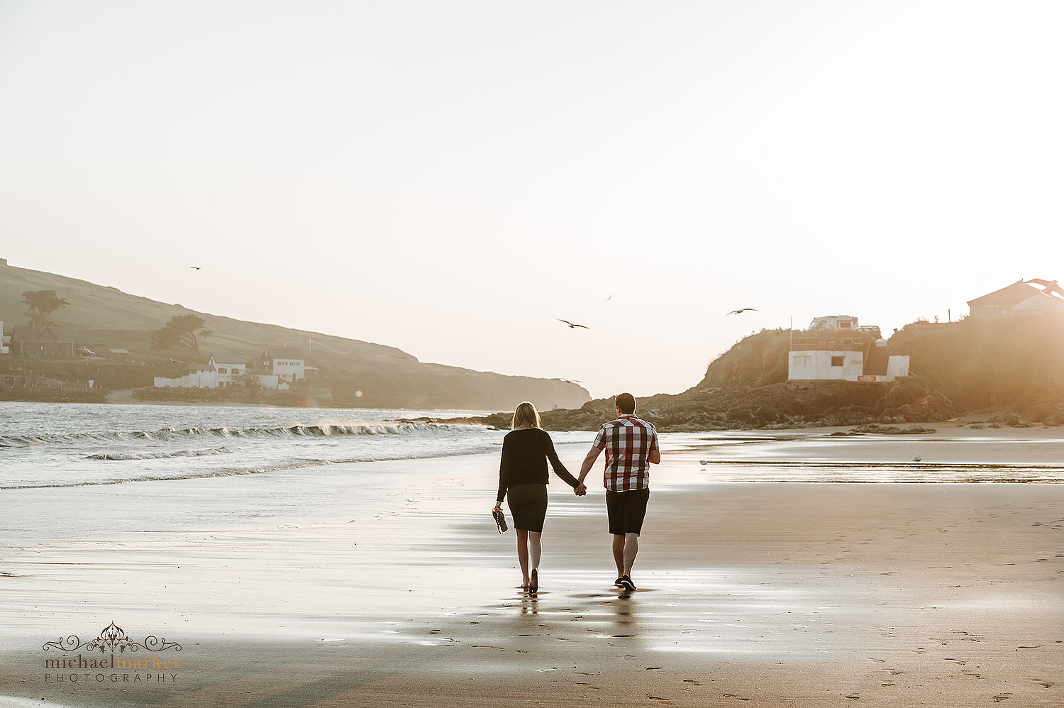 A couple walking towards the sunset on Bigbury beach