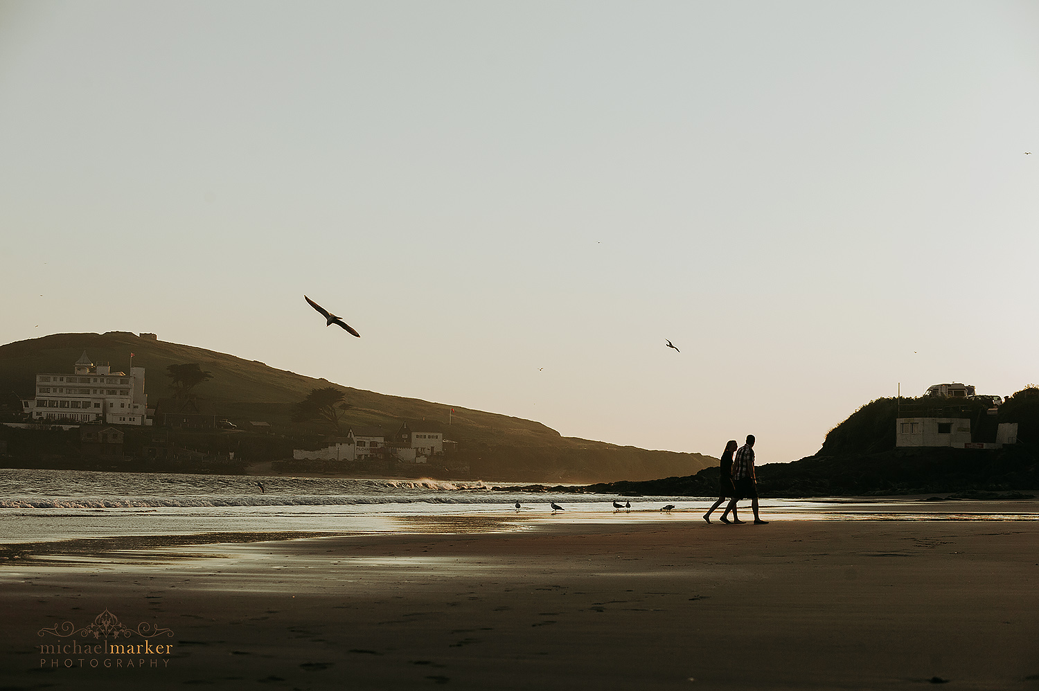 Man and lady walking in Bigbury beach in Devon at Sunset