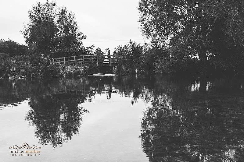 Bride and groom kiss on bridge over stream