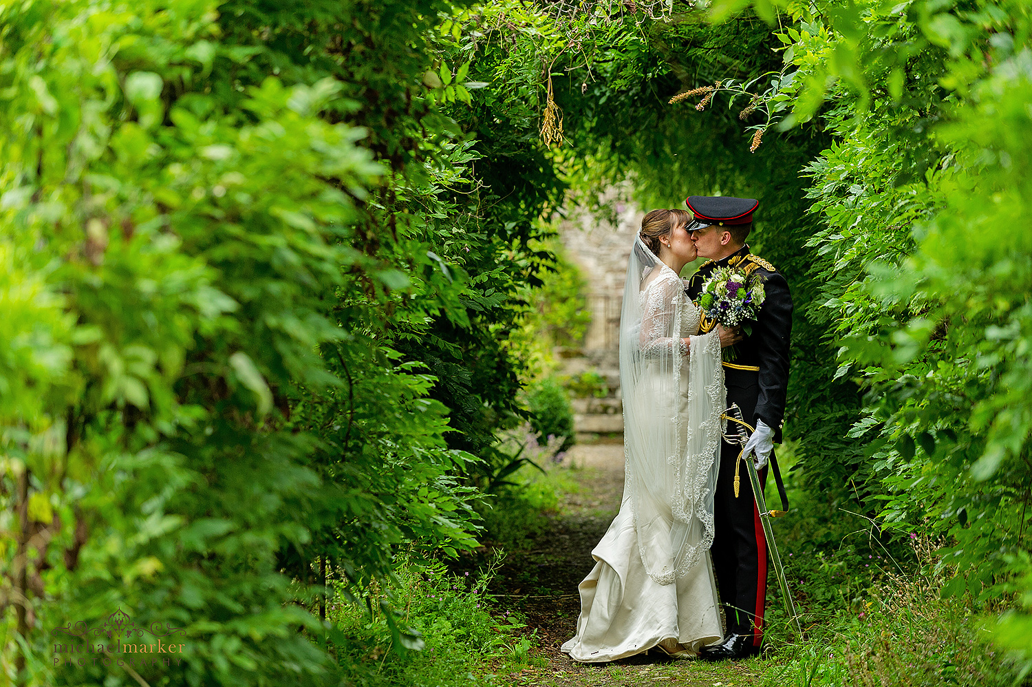 Bride and groom kiss in the wisteria walkway at Pentillie Castle wedding 