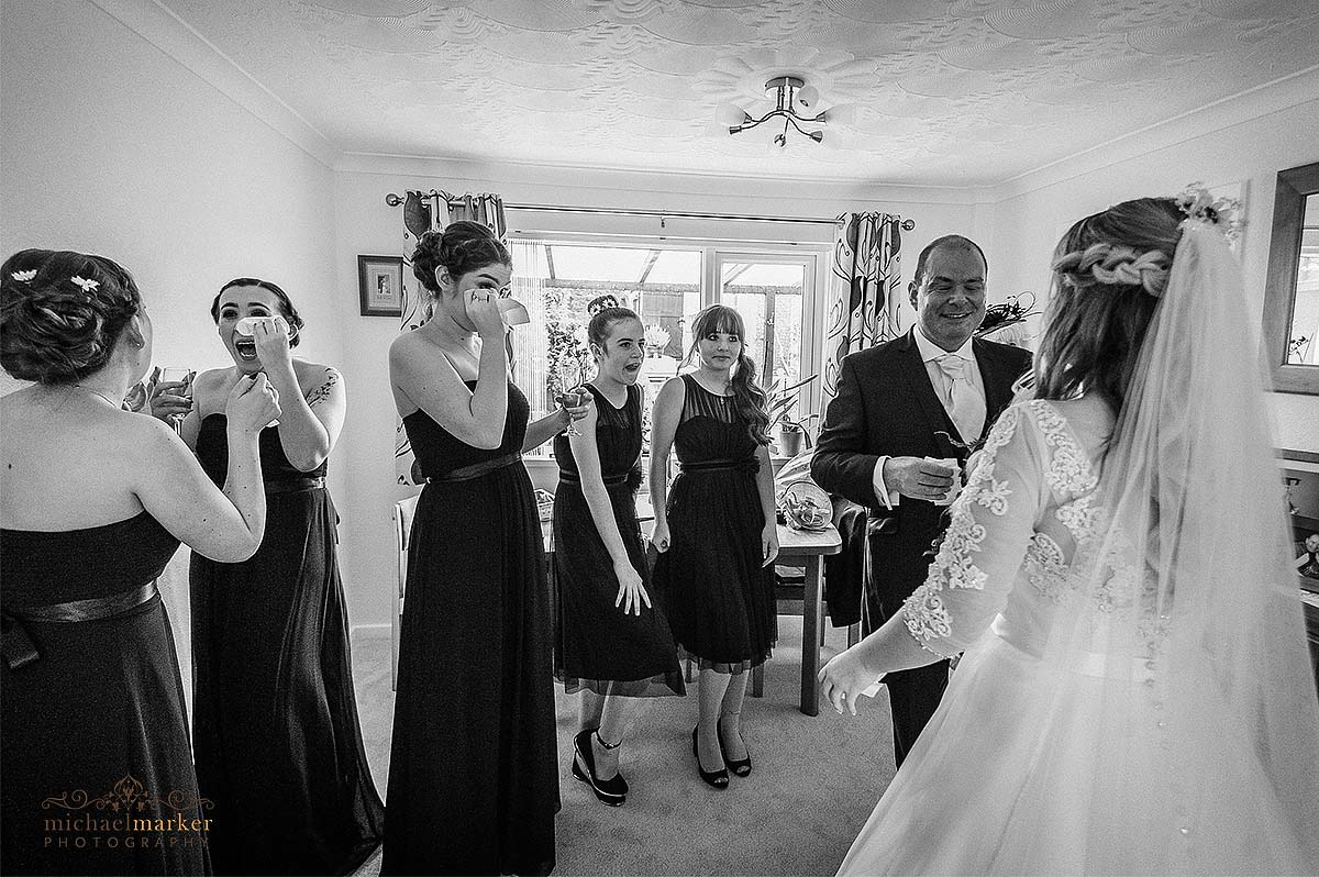 Bridesmaid and father wiping tears when seeing the bride for first look