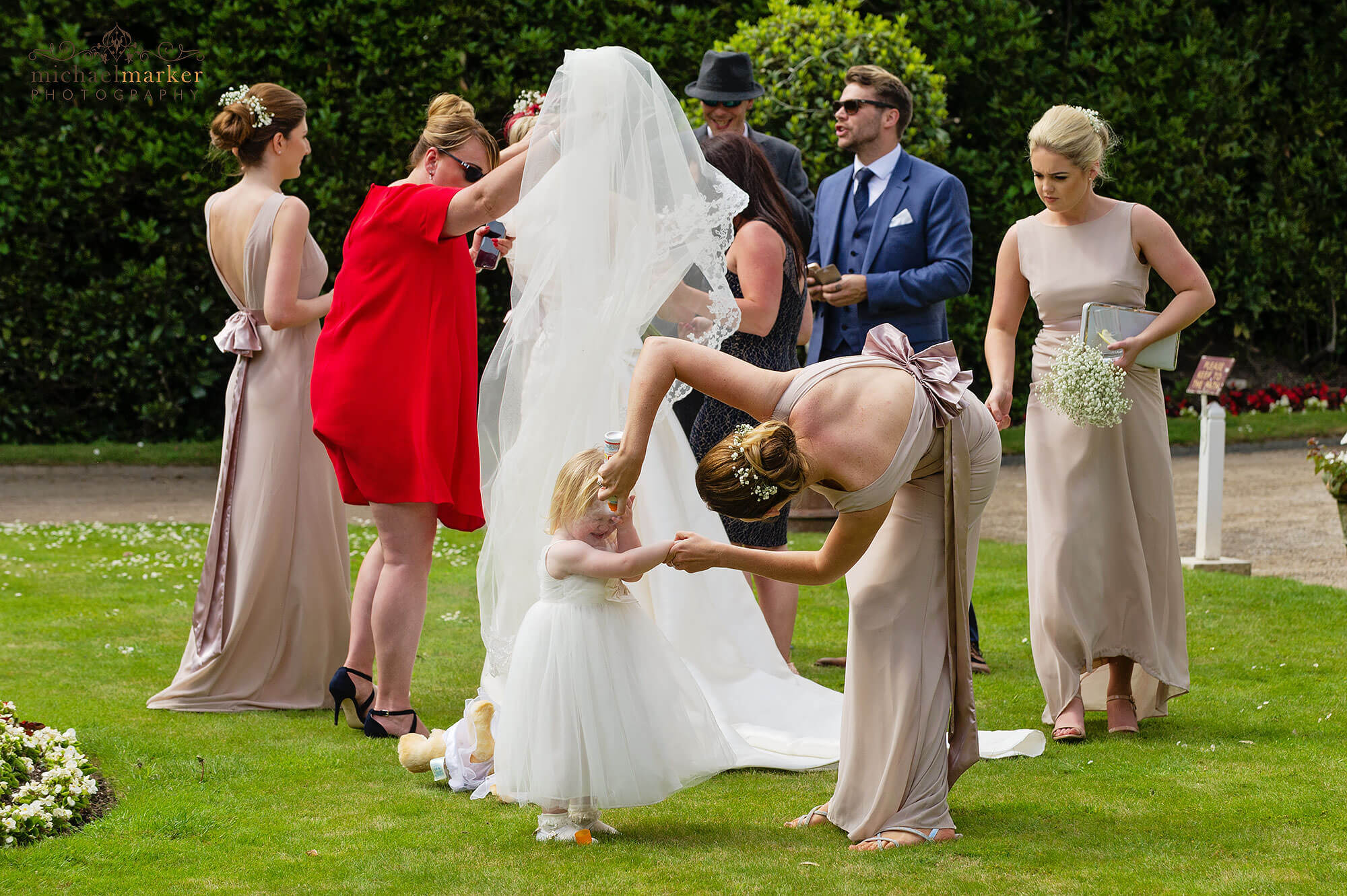 Cornish wedding photographers photo at Mount Edgcumbe of flowergirl not wanting sunscreen applied.