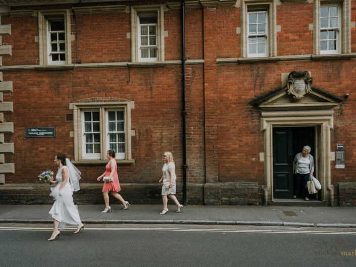 Wiltshire weddings photographers photo of bride, her mother and bridesmaid walk through the city centre of Salisbury