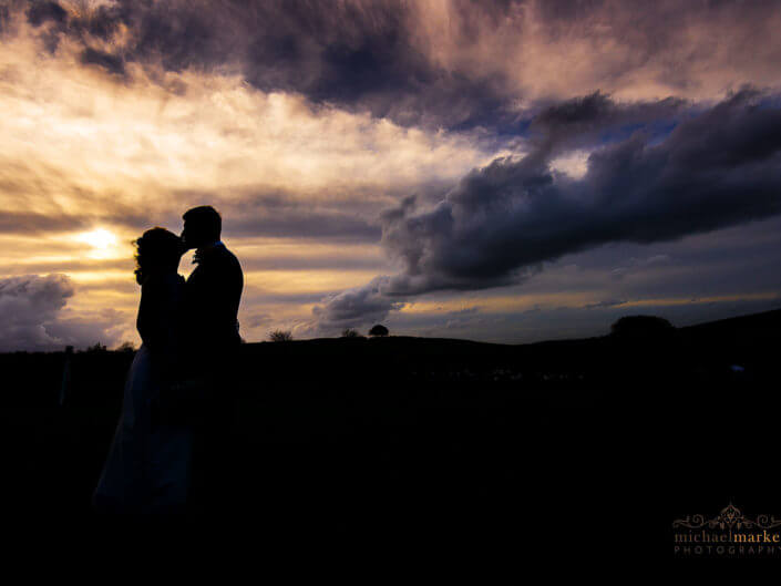 Devon wedding photographers sunset silhouette of bride and groom kissing at Dunwell Farm wedding venue