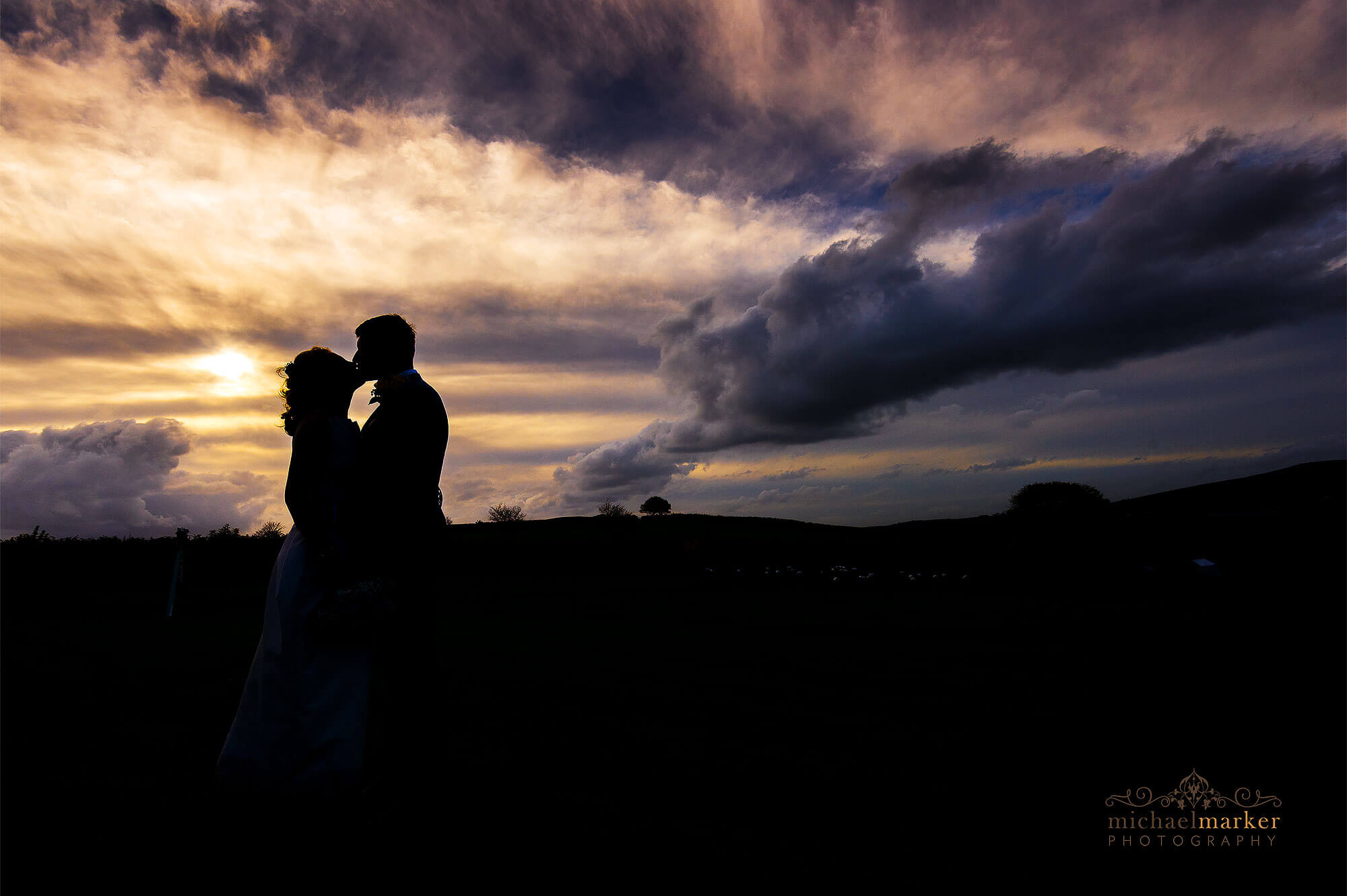 Devon wedding photographers sunset silhouette of bride and groom kissing at Dunwell Farm wedding venue