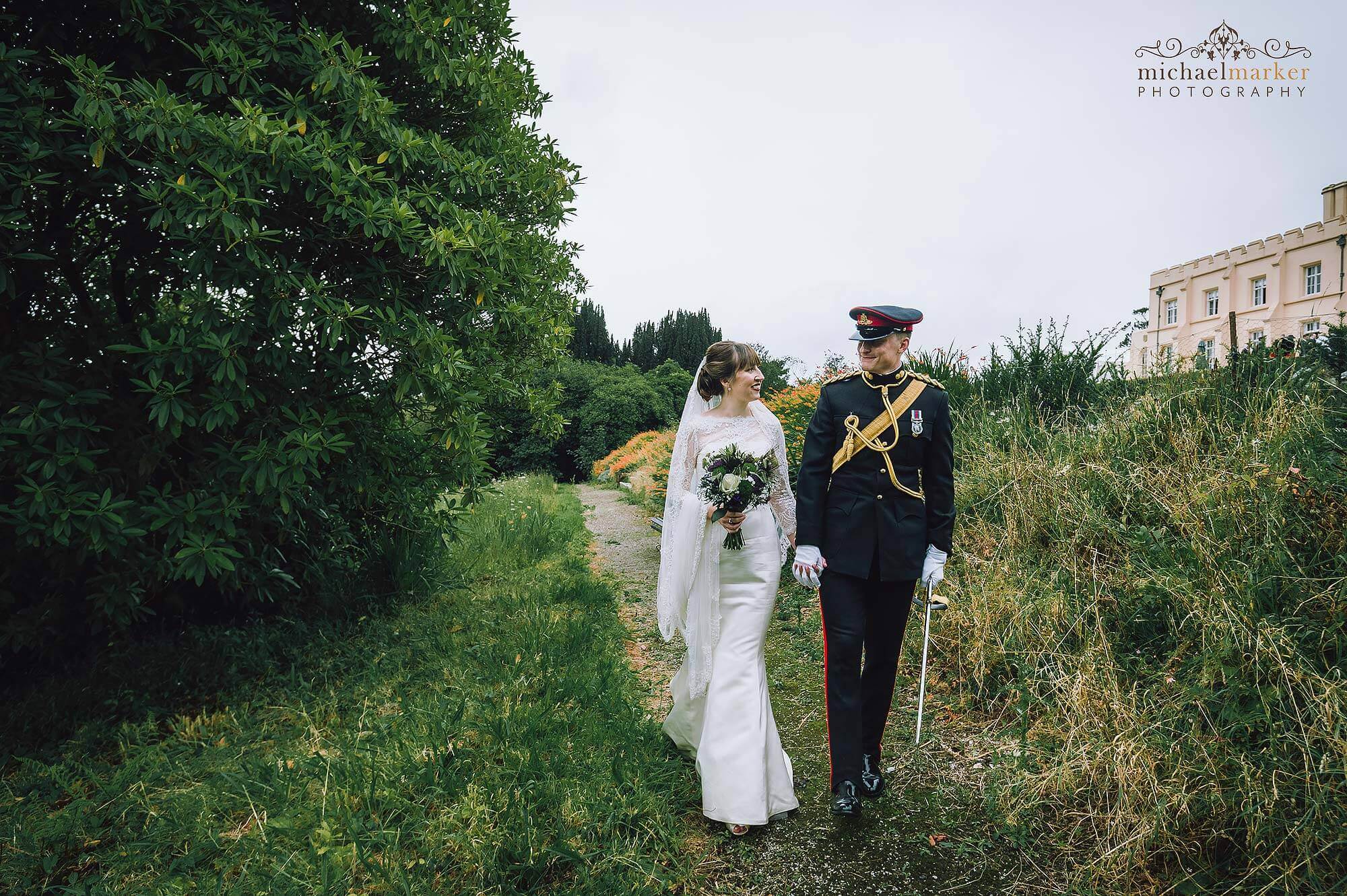 Bride and military officer groom walk in gardens of beautiful Pentillie Castle on their wedding day