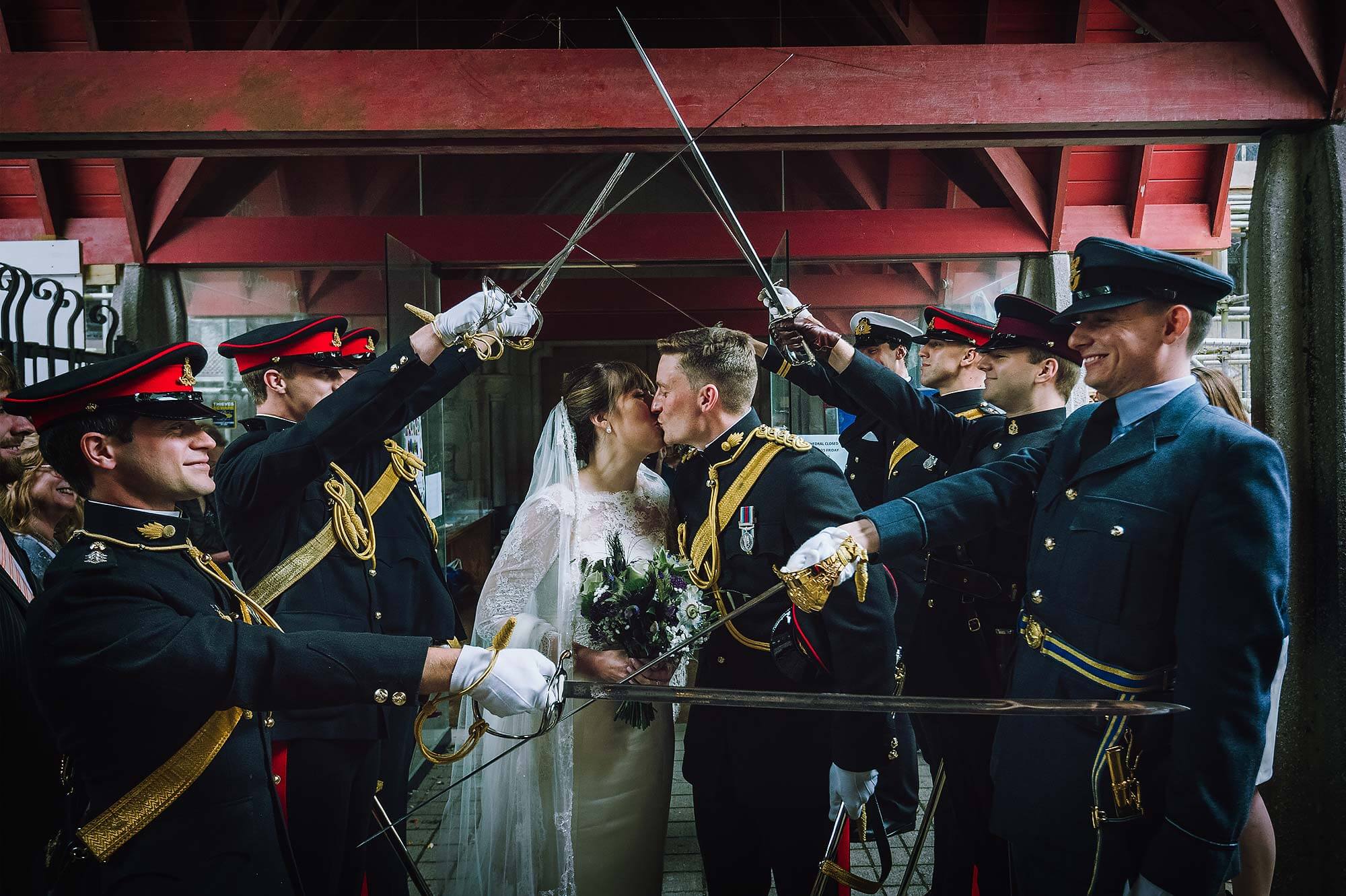 Groom and bride kiss outside Catholic Cathedral in Plymouth as part of Army tradition.