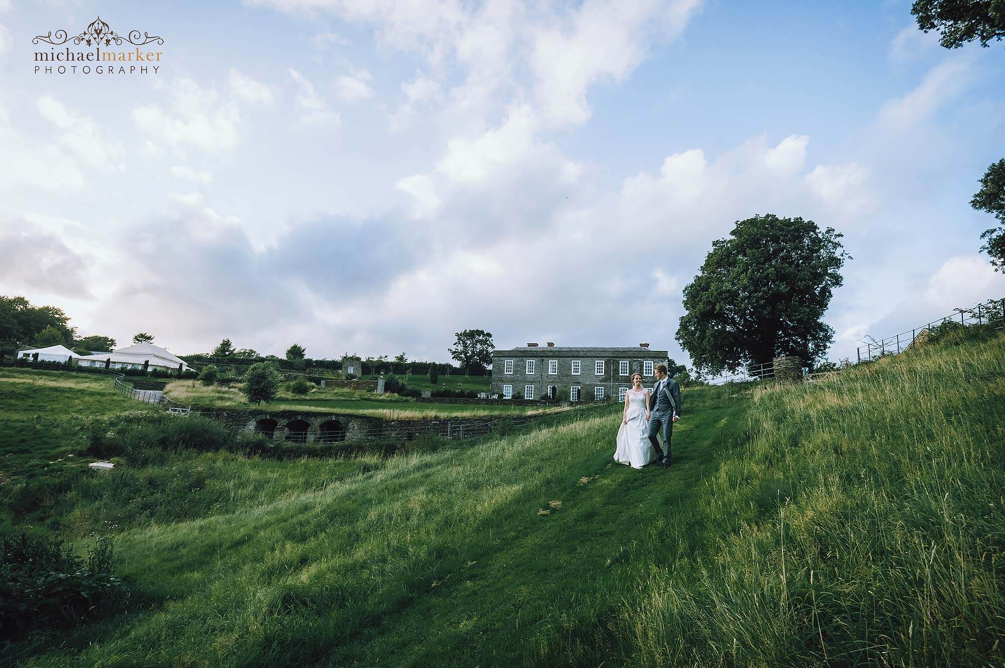 Bride and groom walking in the fields of luxury wedding venue Shilstone House.